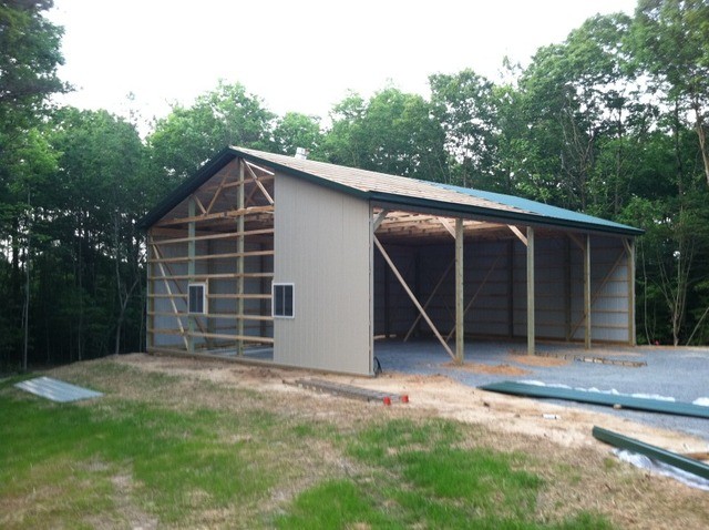Crimson red pole barn workshop with a white roof, a large white door, and a small white door